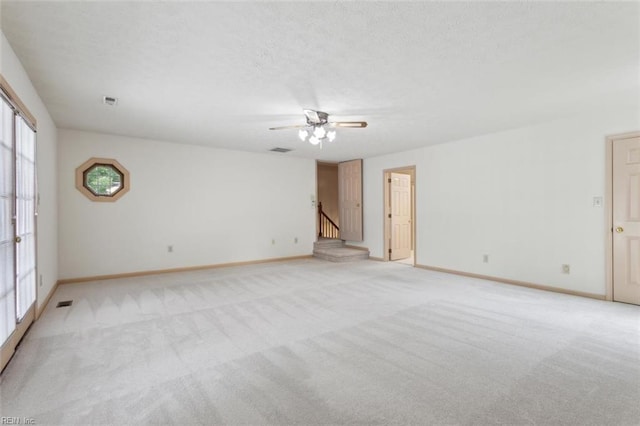 unfurnished room with baseboards, a textured ceiling, a ceiling fan, and light colored carpet