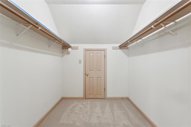 walk in closet with light carpet