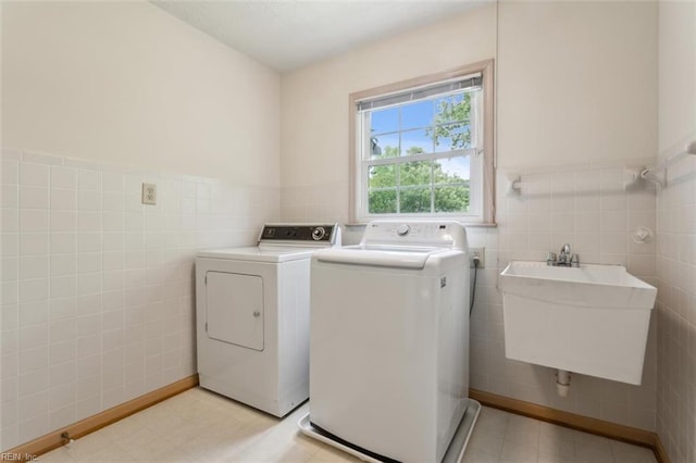 laundry area featuring tile walls, washer and dryer, a sink, and laundry area