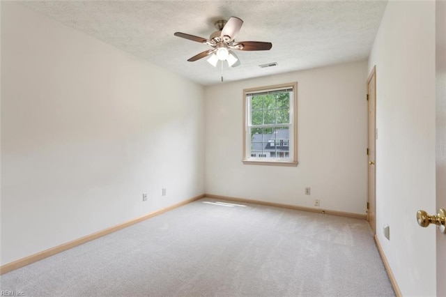 spare room with a textured ceiling, visible vents, a ceiling fan, and light carpet