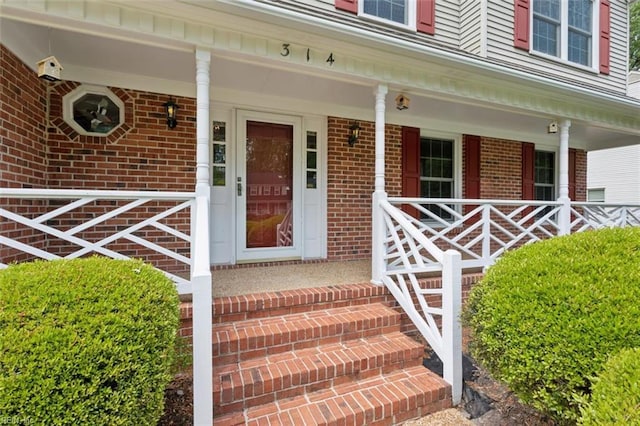entrance to property with a porch and brick siding
