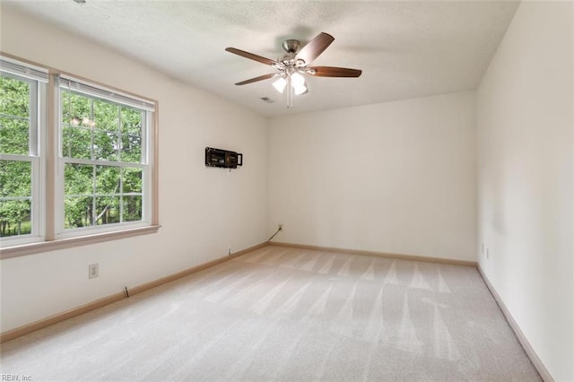 spare room with light colored carpet, ceiling fan, and baseboards