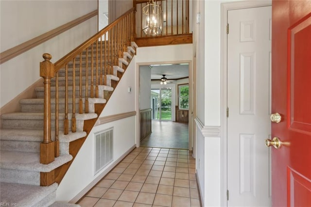 staircase featuring tile patterned floors, baseboards, visible vents, and ceiling fan