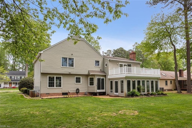 rear view of house with central AC unit, a balcony, crawl space, a lawn, and a sunroom