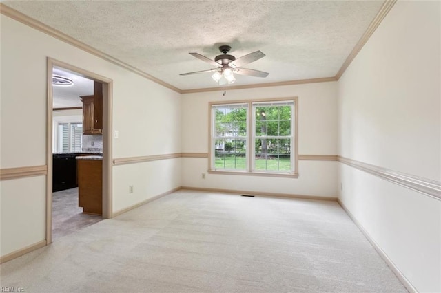 spare room with a textured ceiling, a ceiling fan, light colored carpet, and ornamental molding