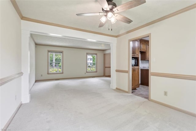spare room featuring light carpet, baseboards, ornamental molding, and ceiling fan