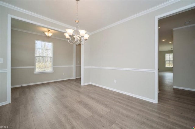 unfurnished room with a chandelier, wood finished floors, crown molding, and baseboards