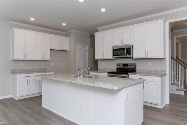 kitchen with crown molding, wood finished floors, a sink, stainless steel appliances, and white cabinets