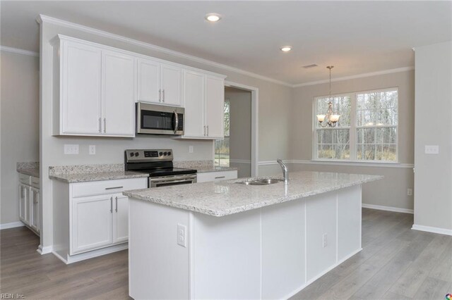kitchen with white cabinets, ornamental molding, a sink, light wood-type flooring, and appliances with stainless steel finishes
