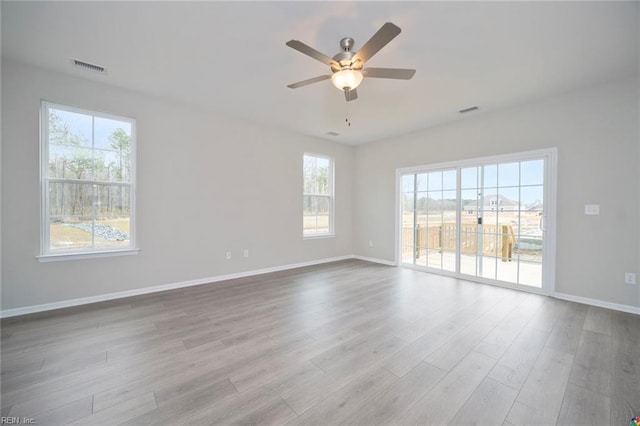 empty room with baseboards, a ceiling fan, wood finished floors, and visible vents