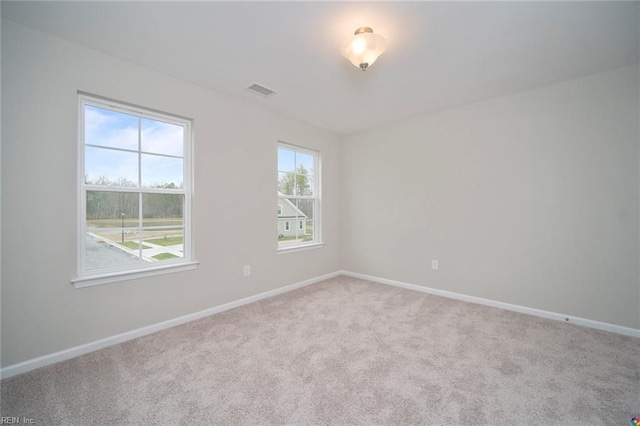 carpeted spare room with visible vents and baseboards