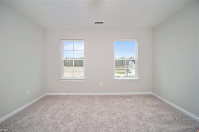 carpeted spare room with plenty of natural light, visible vents, and baseboards