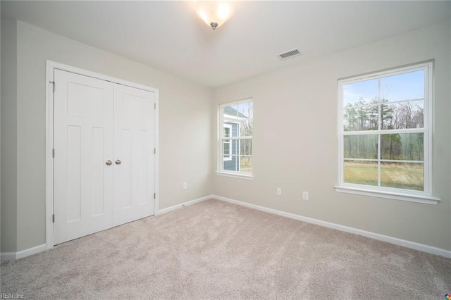 unfurnished bedroom with baseboards, a closet, visible vents, and carpet