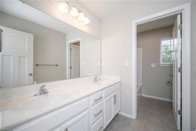 bathroom featuring baseboards, tile patterned floors, a sink, and double vanity
