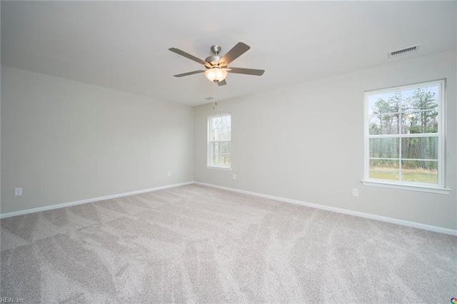 carpeted spare room with visible vents, a ceiling fan, and baseboards