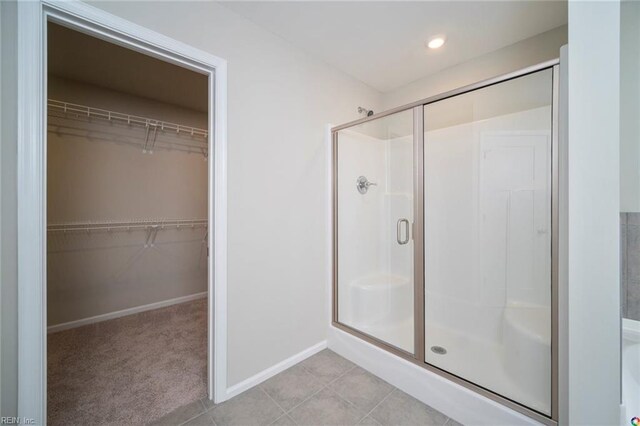 bathroom featuring a walk in closet, a shower stall, baseboards, and recessed lighting
