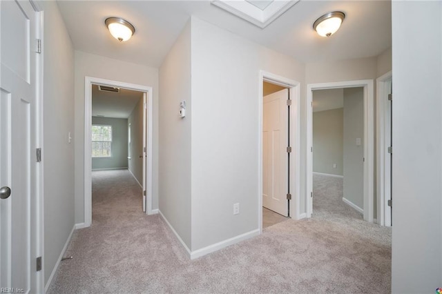 hallway featuring carpet floors, visible vents, and baseboards