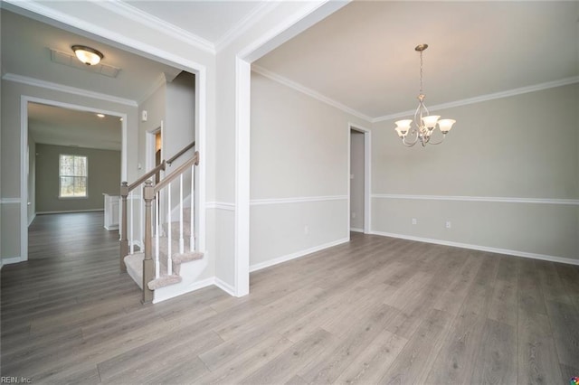 empty room with baseboards, an inviting chandelier, wood finished floors, stairs, and crown molding