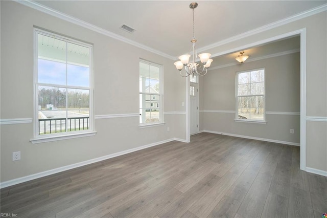 unfurnished room featuring visible vents, baseboards, an inviting chandelier, wood finished floors, and crown molding