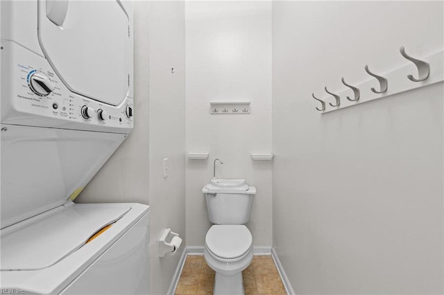 half bathroom with stacked washer and clothes dryer, tile patterned flooring, toilet, and baseboards