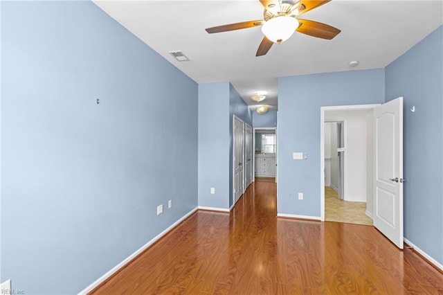unfurnished bedroom featuring baseboards, wood finished floors, and visible vents