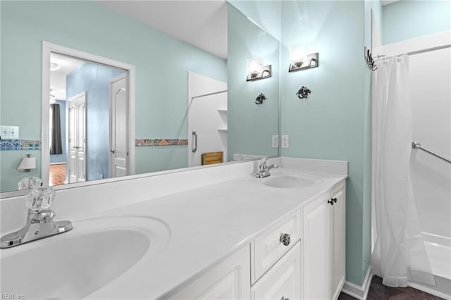 bathroom featuring a shower with curtain, a sink, and double vanity
