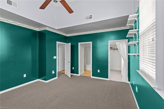 unfurnished bedroom featuring visible vents, carpet, and a walk in closet