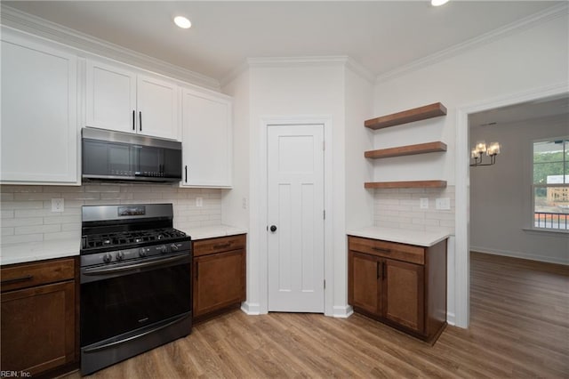 2227 Captiva Ln, Chesapeake, VA 23321 - kitchen featuring white cabinets, black gas range oven, light countertops, light wood-style floors, and crown molding