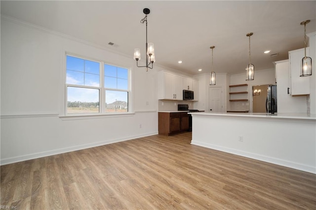 kitchen with light wood-type flooring, pendant lighting, light countertops, white cabinets, and ornamental molding