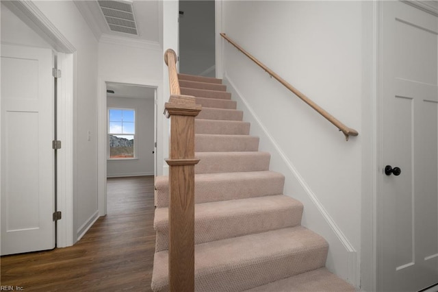 staircase with wood finished floors, visible vents, crown molding, and baseboards