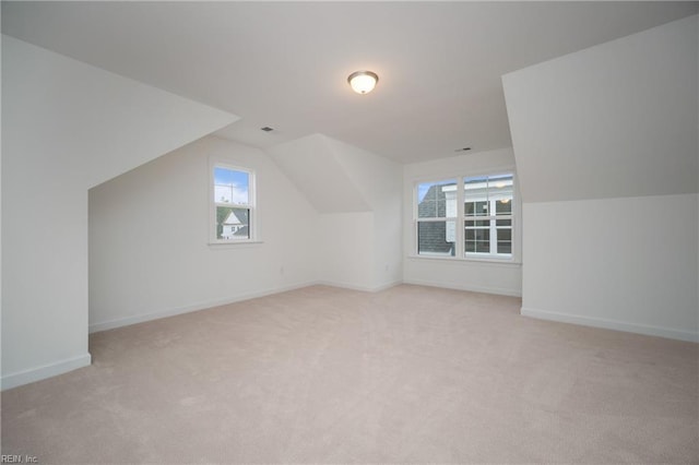 additional living space with light carpet, vaulted ceiling, visible vents, and baseboards