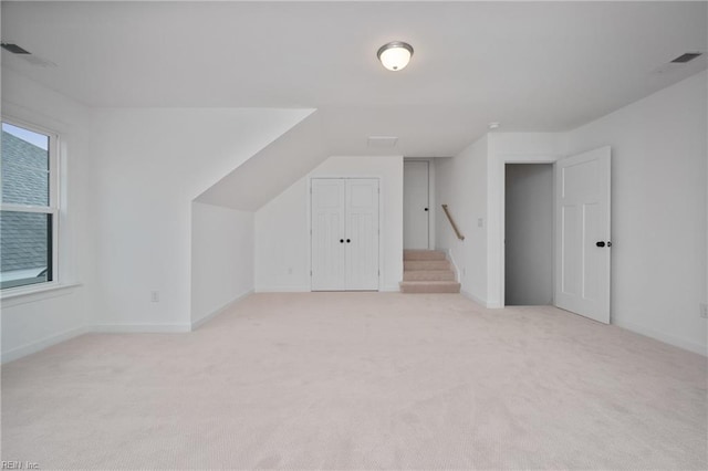 additional living space featuring light colored carpet, baseboards, and stairs