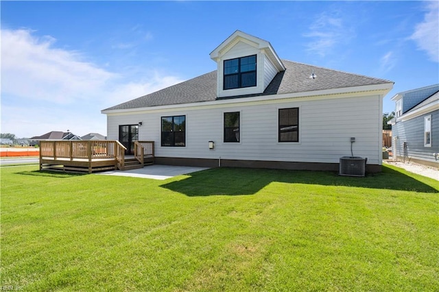 rear view of property with a yard, roof with shingles, central air condition unit, and a deck