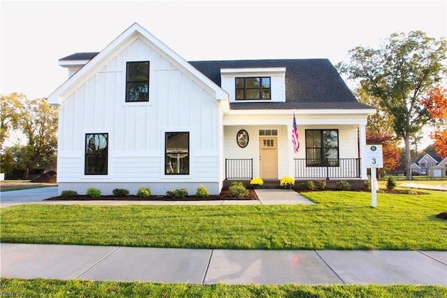 modern farmhouse with board and batten siding, a front yard, and covered porch