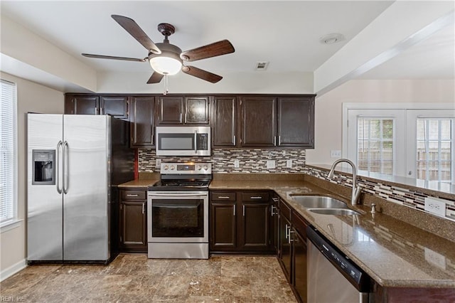 kitchen featuring dark brown cabinets, appliances with stainless steel finishes, decorative backsplash, and a sink