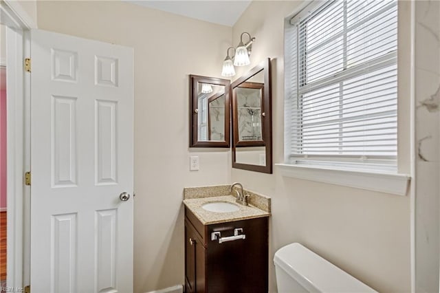 bathroom with toilet, vanity, and a healthy amount of sunlight