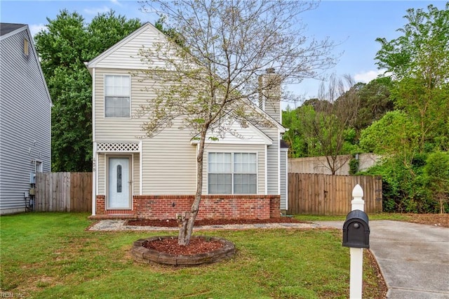 view of front facade featuring brick siding, a front yard, a chimney, and fence