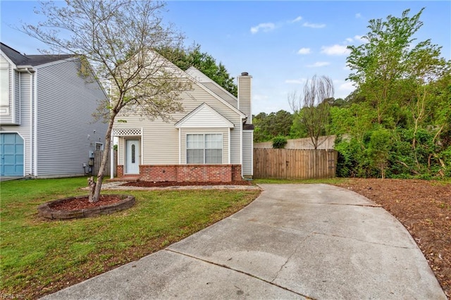 view of front of house with fence, a chimney, brick siding, and a front yard