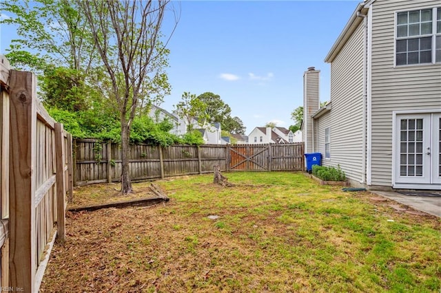 view of yard featuring a fenced backyard and french doors