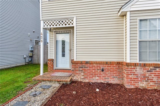 property entrance featuring fence and brick siding