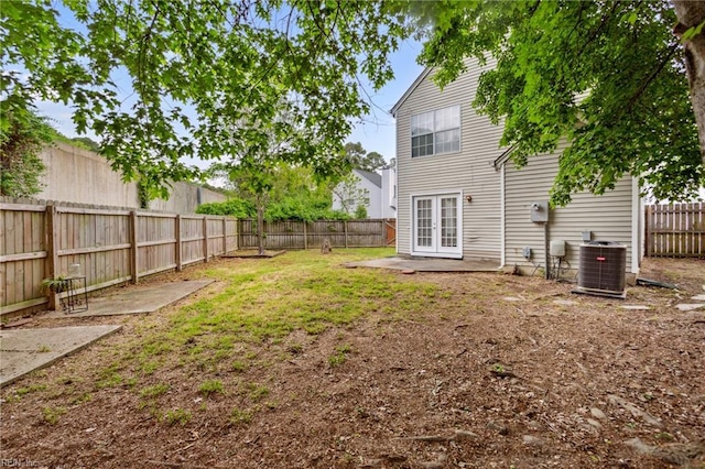view of yard with central air condition unit, a fenced backyard, and french doors