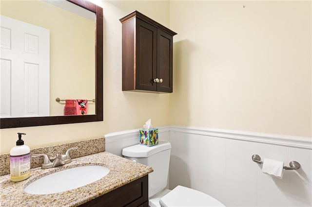 half bathroom featuring wainscoting, vanity, and toilet