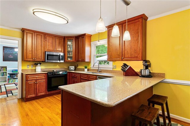 kitchen featuring a peninsula, a kitchen breakfast bar, a sink, stainless steel microwave, and black / electric stove