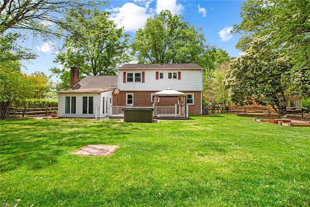 back of property featuring a gazebo, a lawn, a hot tub, and a fenced backyard