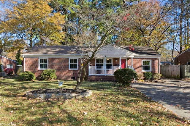 ranch-style house featuring driveway, covered porch, fence, a front yard, and brick siding