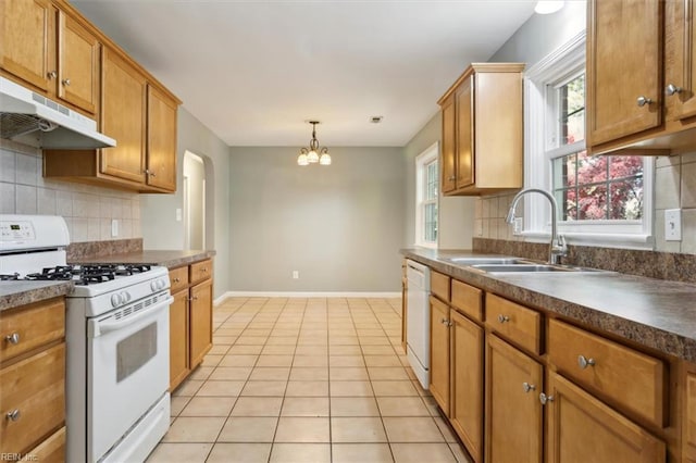 kitchen with a sink, under cabinet range hood, white appliances, baseboards, and a notable chandelier