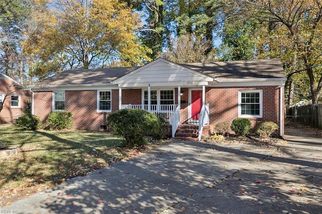 ranch-style home with a front lawn, driveway, a porch, fence, and brick siding