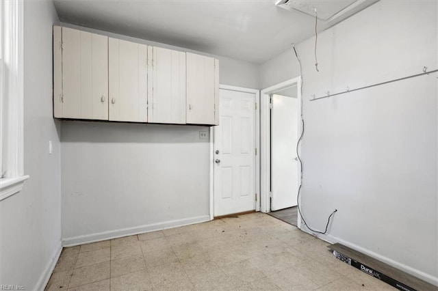 clothes washing area with attic access, baseboards, and light floors