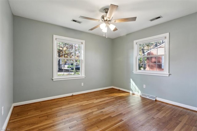 empty room with baseboards, wood finished floors, visible vents, and a ceiling fan