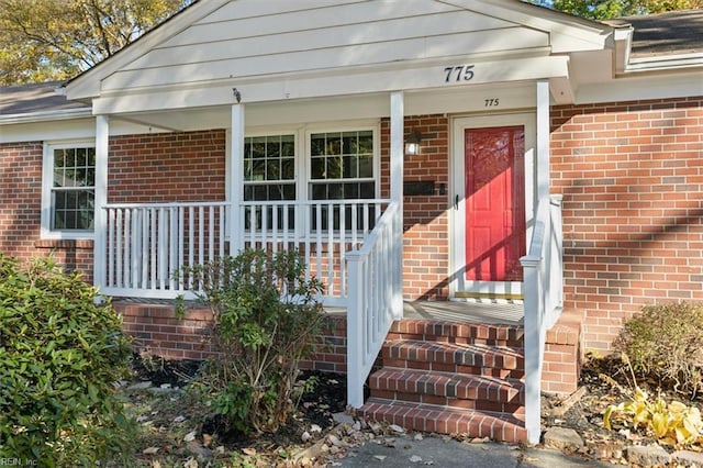 property entrance with a porch and brick siding